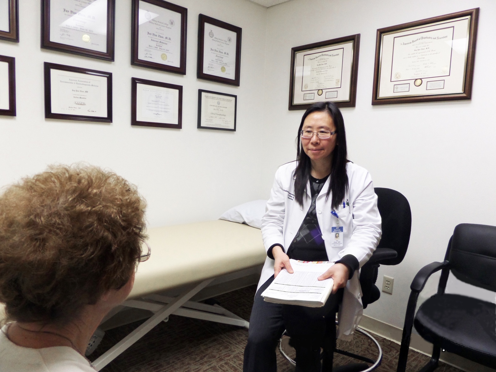 Dr. Joy Zhao, M.D., Board Certified Neurologist and Subspecialist, Founder of Integrated Neurology Health Services, speaking with a patient in an examining room